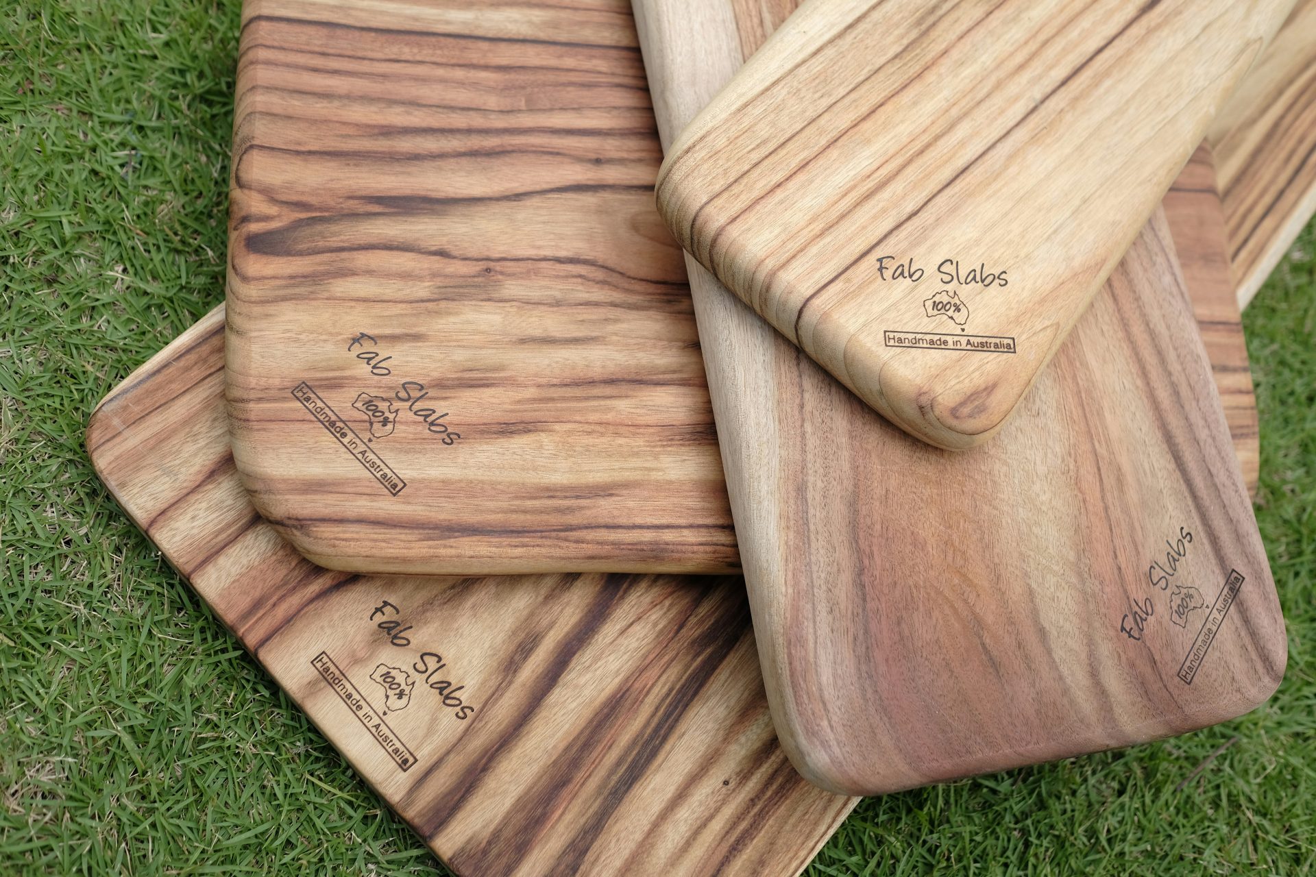 a pile of wooden cutting boards sitting on top of a green field
